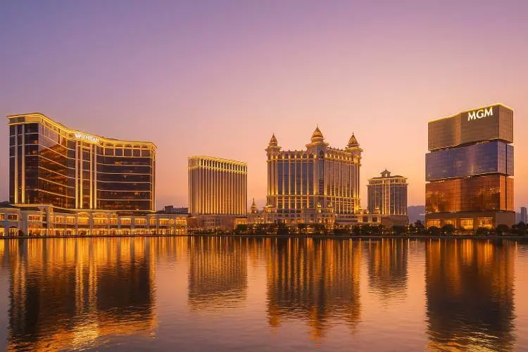 A photo-realistic nighttime view of the Macau skyline with illuminated casinos, reflecting on the water.
